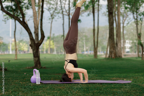 Schilderij op canvas Asian girl practicing yoga amidst lush trees, providing a perfect visual for digital detox and self-care