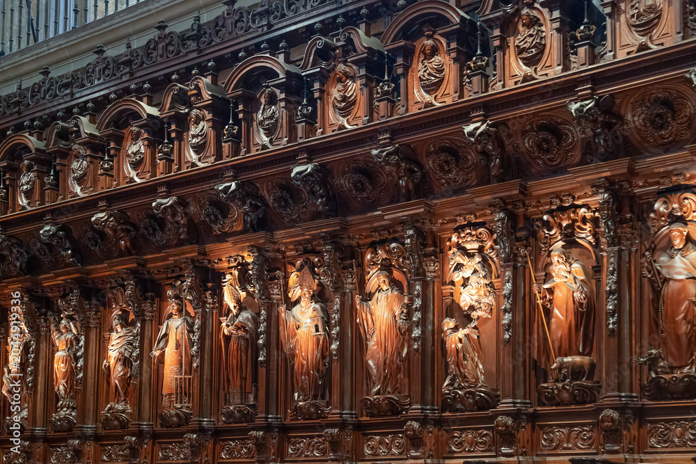 Obraz premium Close-up view of the intricate and ornate Baroque dark wood carvings inside the Cathedral of Malaga, Spain. The masterfully sculpted religious figures and saints decorate the historic choir stalls.