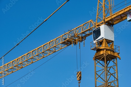 Fotografía Yellow tower crane cabin and jib arm against a clear blue sky