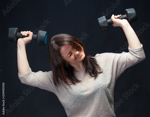 Woman exercising with black dumbbells