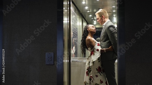 Schilderij op canvas A handsome young man and a beautiful woman look at each other and smile while standing in an elevator