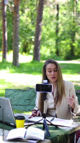 In this vertical video, a beautiful woman conducts an online consultation surrounded by trees. Her friendly demeanor and expert knowledge create an inviting space for insightful discussions.