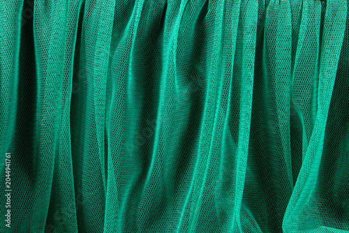 A close-up view of draped green mesh fabric with a fine net texture and soft folds