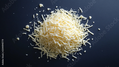 Grated premium cheddar cheese isolated on blue background. Fresh grated cheese for toppings and cooking