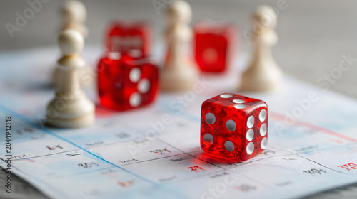 A vibrant close-up of red dice and wooden game pieces on a calendar, capturing the essence of strategy and chance in leisure activities. Perfect for game night themes.