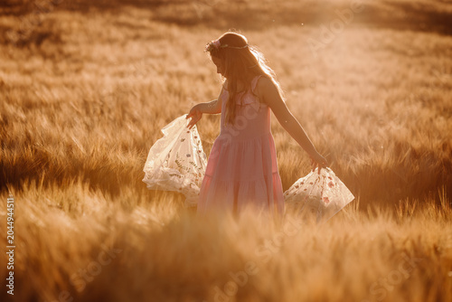 Bild auf Leinwand girl in pink dress holding floral shawl open in hazy summer field
