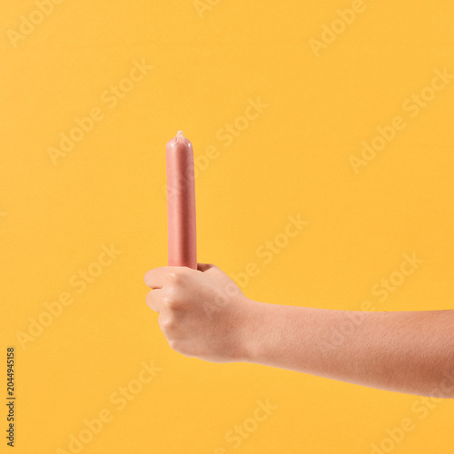 Female Hands Holding Sausage on Yellow Background