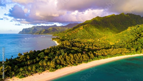 Lush green mountains meet a sandy beach and turquoise ocean at sunrise