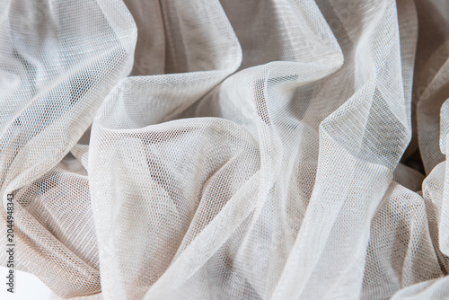 Crumpled cream beige mesh fabric showing fine net texture and soft irregular folds