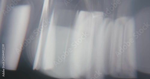 Abstract gray background with moving lens flares and refractions. Delicate colors bokeh effect for luxury logo display. Grey-blue light leaks on a blurred background with copy space. 