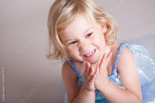 Slika na platnu Delightful Toddler Girl Clapping Hands and Giggling in Natural Studio Light