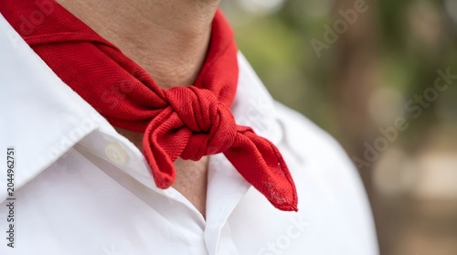 Vibrant red bandana knotted tightly on a participant's neck, showcasing traditional attire during an annualsan fermín festival.