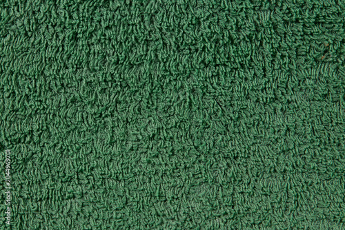 A close-up background texture of soft and fluffy green terry cloth towel fabric with a dense fiber pile surface