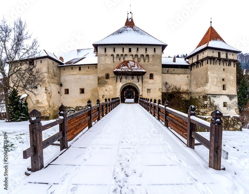 A snow-covered bridge leads to a medieval castle's entrance