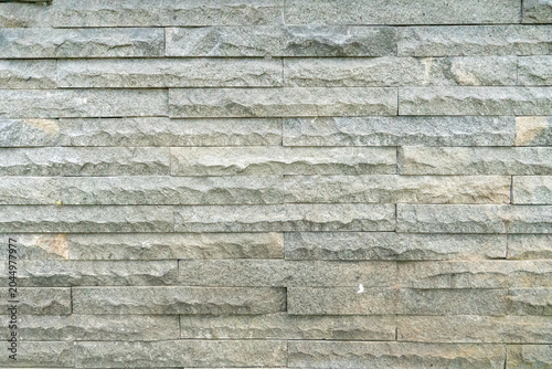 Natural stone walls with a rough, chiseled texture. Linear natural stone or granite tiles arranged horizontally.