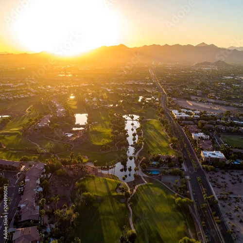 Aerial view of a golf course at sunset with a winding waterway and roads