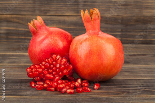 Red juicy pomegranate on a wooden background.