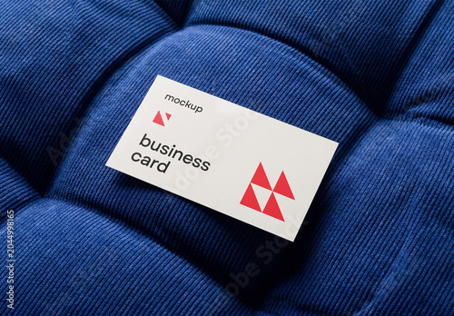 High-angle shot of a blank business card mockup resting on a blue tufted corduroy velvet fabric texture
