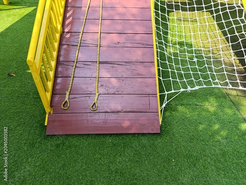 Bright Yellow Playground Ramp with Rope Handles Over Green Turf