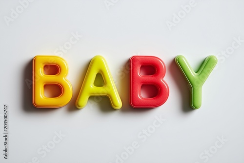 Word BABY Spelled Out in Colorful 3D Alphabet Magnets on Clean White Background