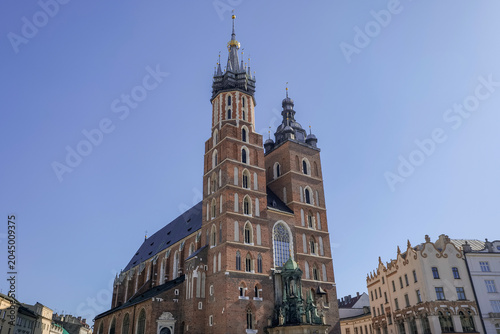 St. Mary's Basilica stands tall in Krakow's main square with blue skies above and historical buildings nearby