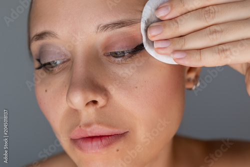 Cuadro en lienzo Close beauty portrait of a young woman removing eyeliner with a cotton pad