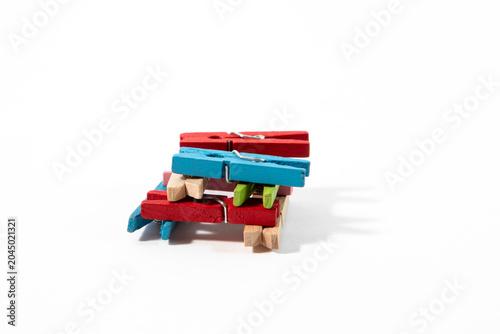Colorful blue, green, and red wooden clothespins stacked together on a clean white background