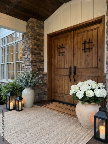 A modern house entrance with wooden doors, potted plants, and lanterns