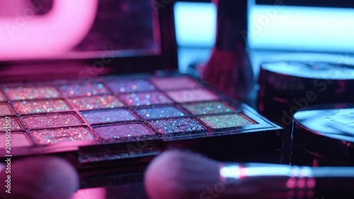 Makeup artist applies colorful eyeshadows with brushes on a table indoors