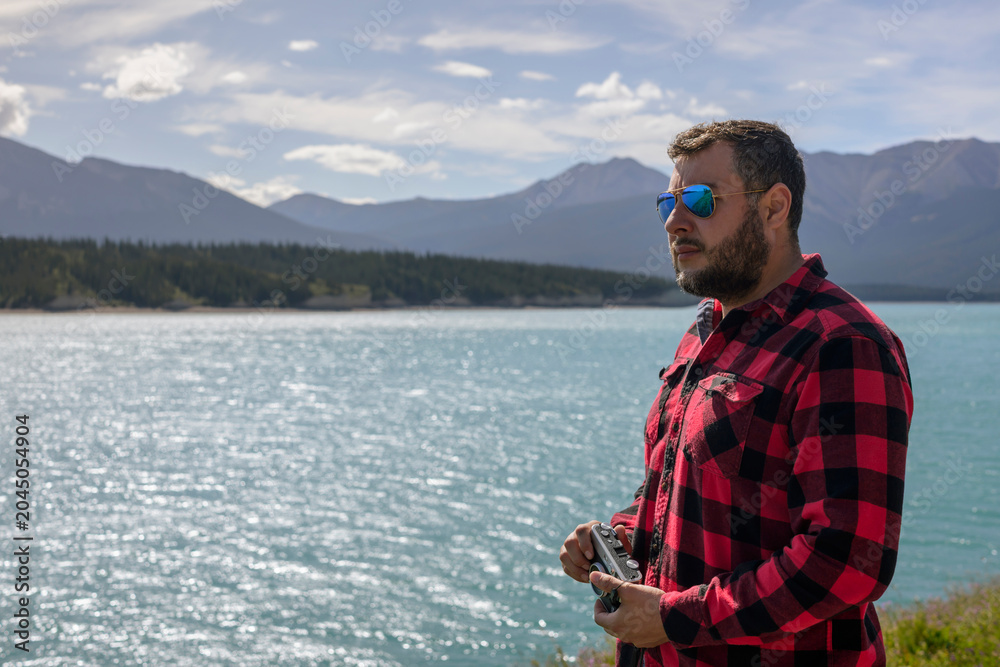 Fototapeta premium Man traveler with sunglasses looking at Canada mountain lake