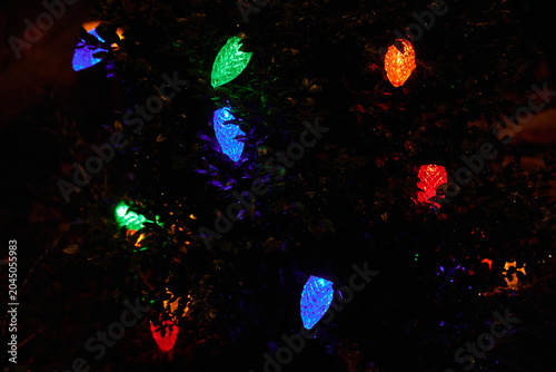 multi-colored large christmas lights at night on a very dark background, blue, red, orange, green with copy space