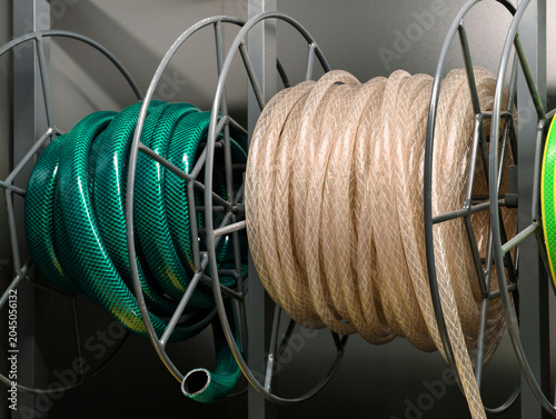 Billede på lærred Two hoses in green and transparent colors arranged in coils are displayed on sto