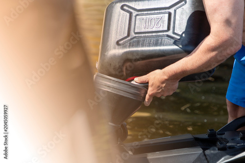 Konstfotografi Man refueling watercraft jet ski with gasoline from a jerry can
