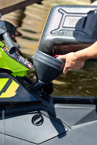 Bilde på lerret Man refueling watercraft jet ski with gasoline from a jerry can