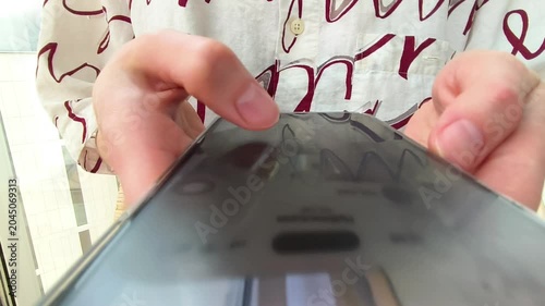 Hands holding a smartphone in close up. The phone is tapped and scrolled while screen content shifts through the clip. Mobile browsing, app use, and online communication concept..