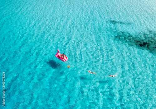 Canvas Print Aerial view of people swimming and relaxing on a giant pink flamingo inflatable in crystal clear turquoise sea, Mallorca, Spain