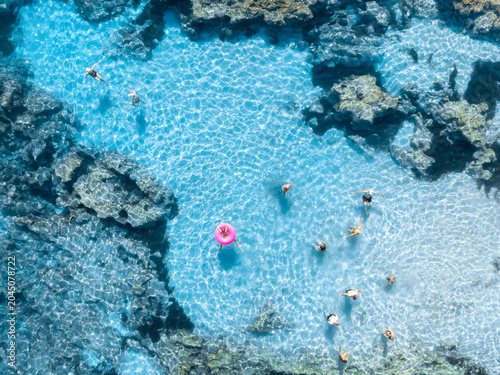 Obraz na plátně Aerial top down view of people swimming in crystal clear turquoise water of natural pool in rocks