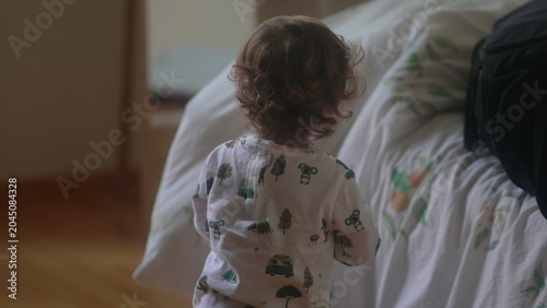 Tableau sur toile Toddler approaching moving bed sheets during playful hide and seek game with old