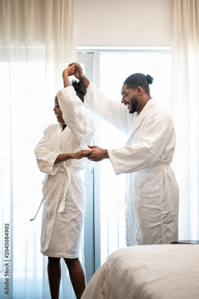 Obraz premium Happy couple dancing in bathrobes during staycation