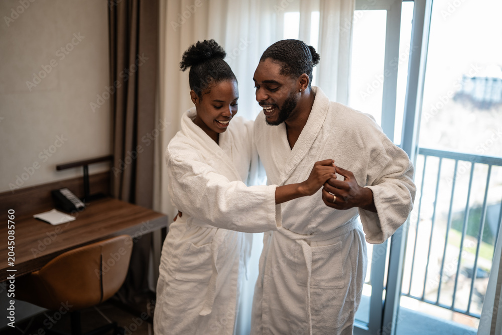 Obraz premium Happy couple dancing in bathrobes enjoying hotel vacation