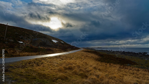 The Sky Slowly Brightens and the Sun Gradually Appears Above the Hills and the Narrow Road by the Sea in Polar Spring. Vestvågøy, Lofoten Islands, Northern Norway.