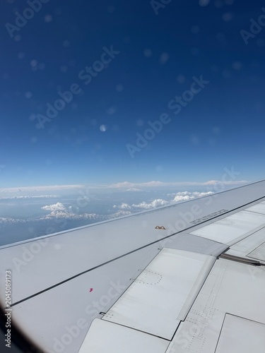 Bild auf Leinwand Airplane Window View: Glimpse the world from above as the sun shines brightly on airplane wing, with clouds and land stretching out below, indicating a journey in progress