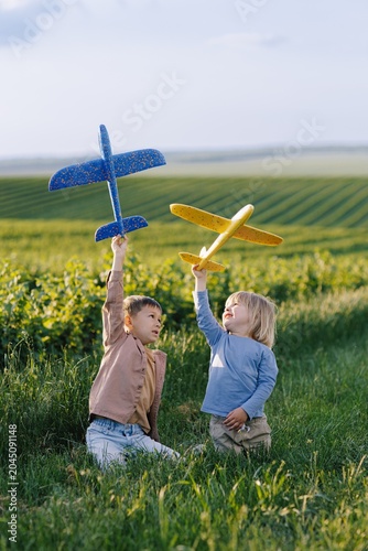 Children playing with toy gliders in green field