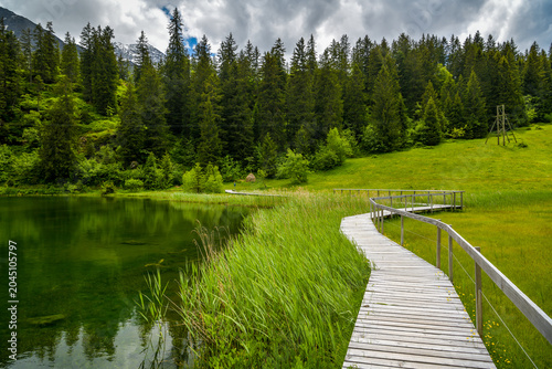 Wooden boardwalk along a calm mountain lake