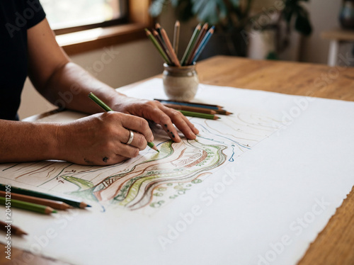 Hands drawing permaculture site design map with pencils