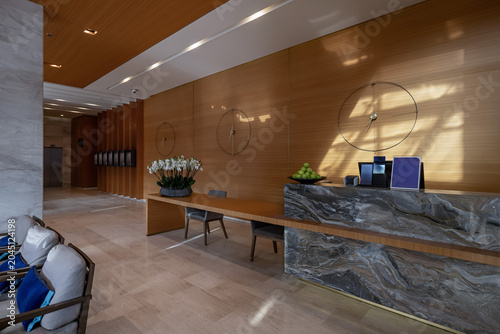 Luxury hotel reception desk made of dark marble with elegant wooden paneling and decorative wall clocks