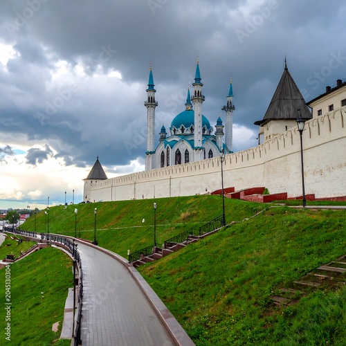 Blue Domed Mosque Rising Behind White Fortress Wall Under Dramatic Cloudy Sky