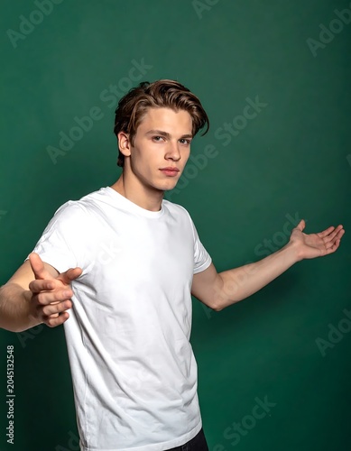 Young Man in White T Shirt Gesturing with Open Arms Against Green Studio Background