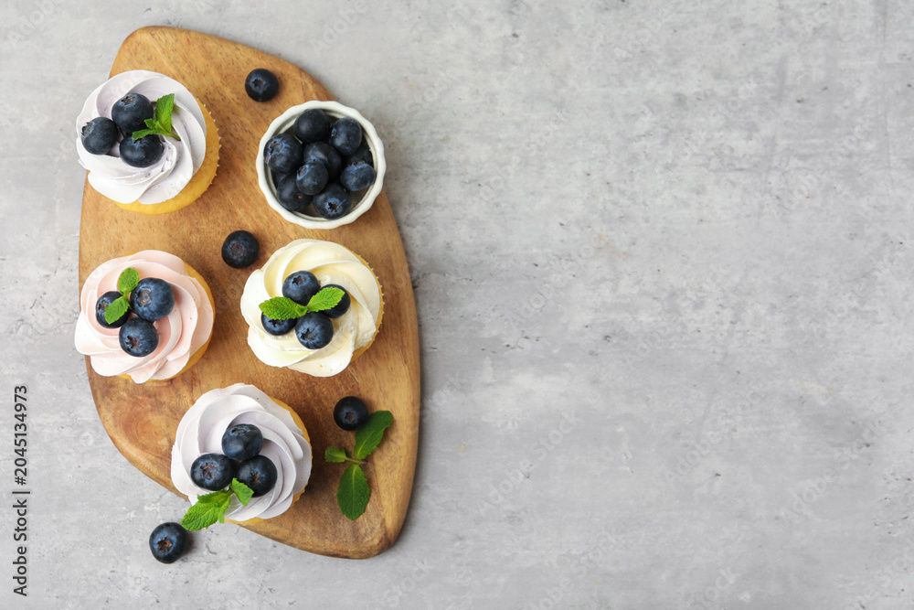 Obraz premium Yummy cupcakes with blueberries and mint on grey table, top view. Space for text