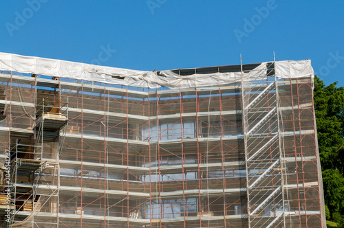 Large building facade covered in construction scaffolding under blue sky development concept